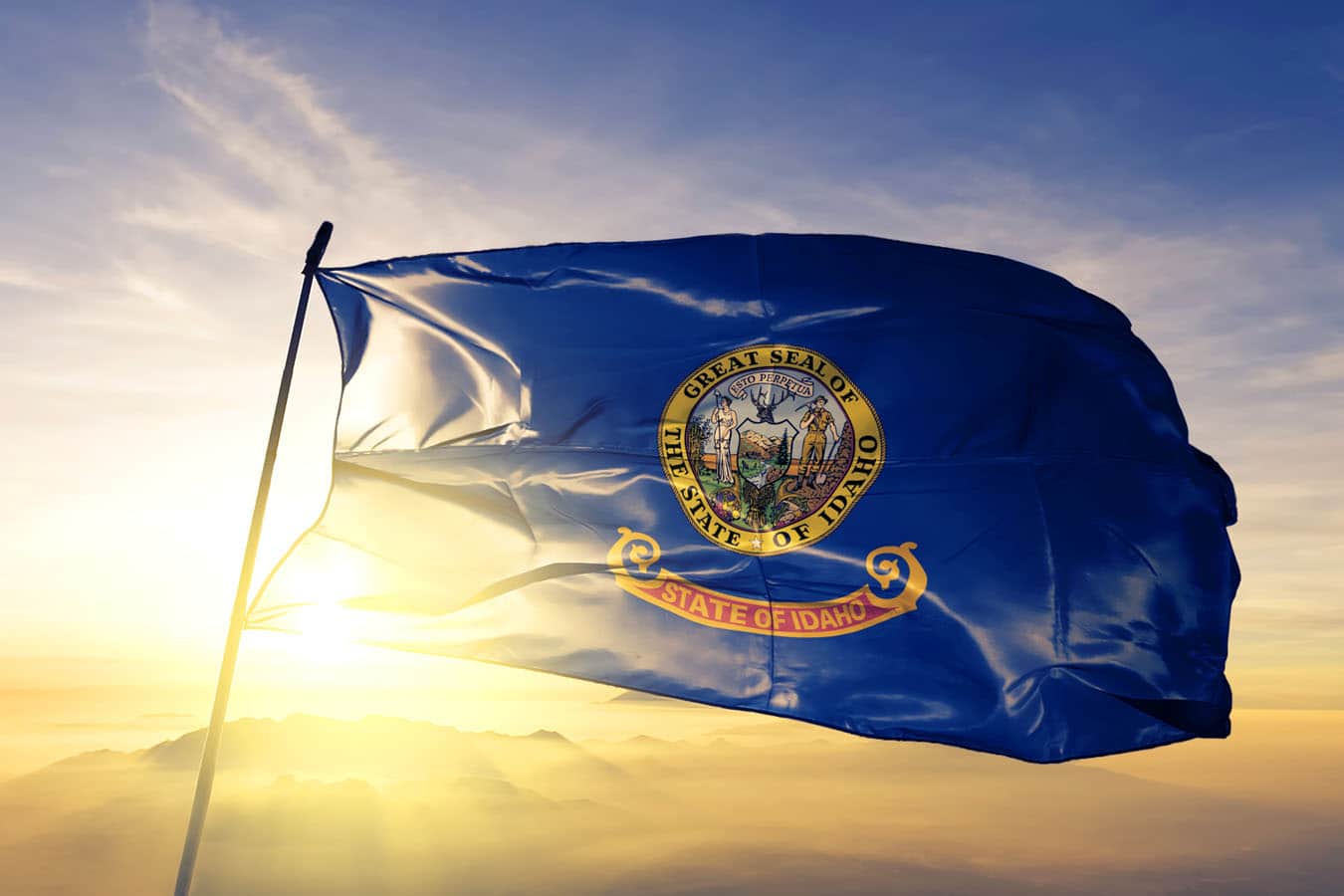 Idaho state of United States flag textile cloth fabric waving on the top sunrise mist fog