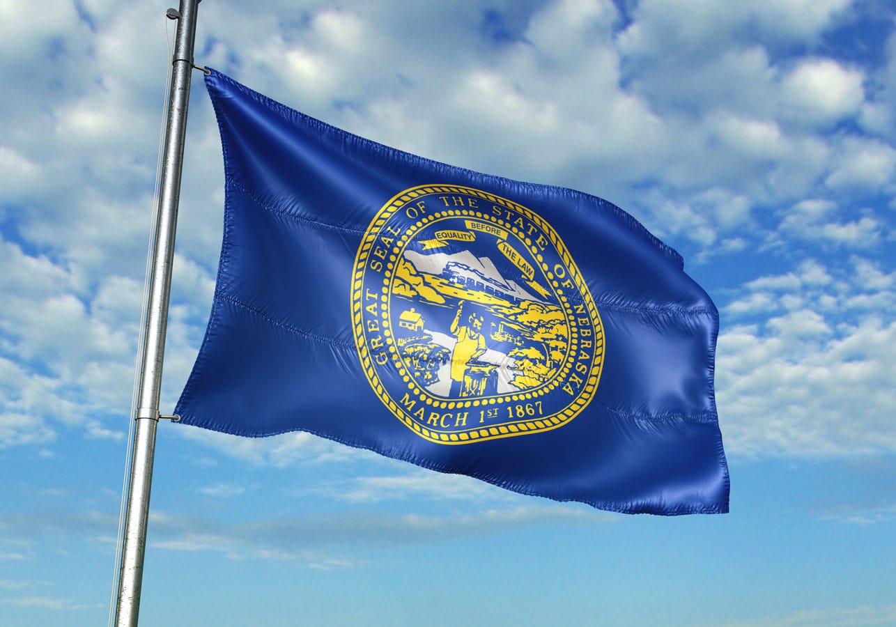 Nebraska state of United States flag waving cloudy sky background